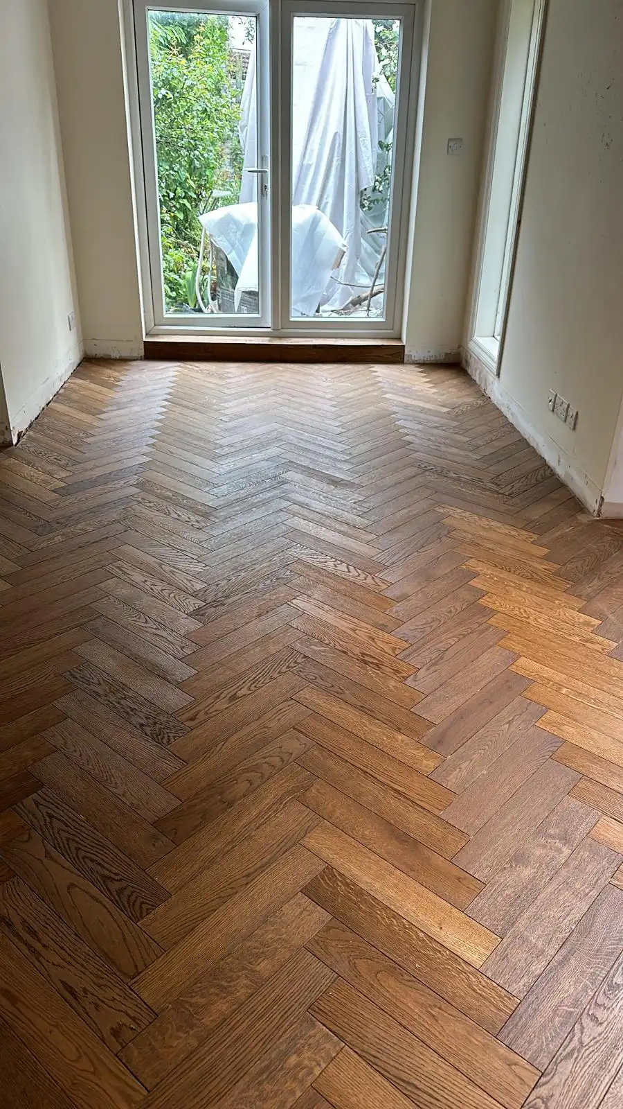 During installation: precision laser set-out of herringbone oak parquet blocks over prepared subfloor